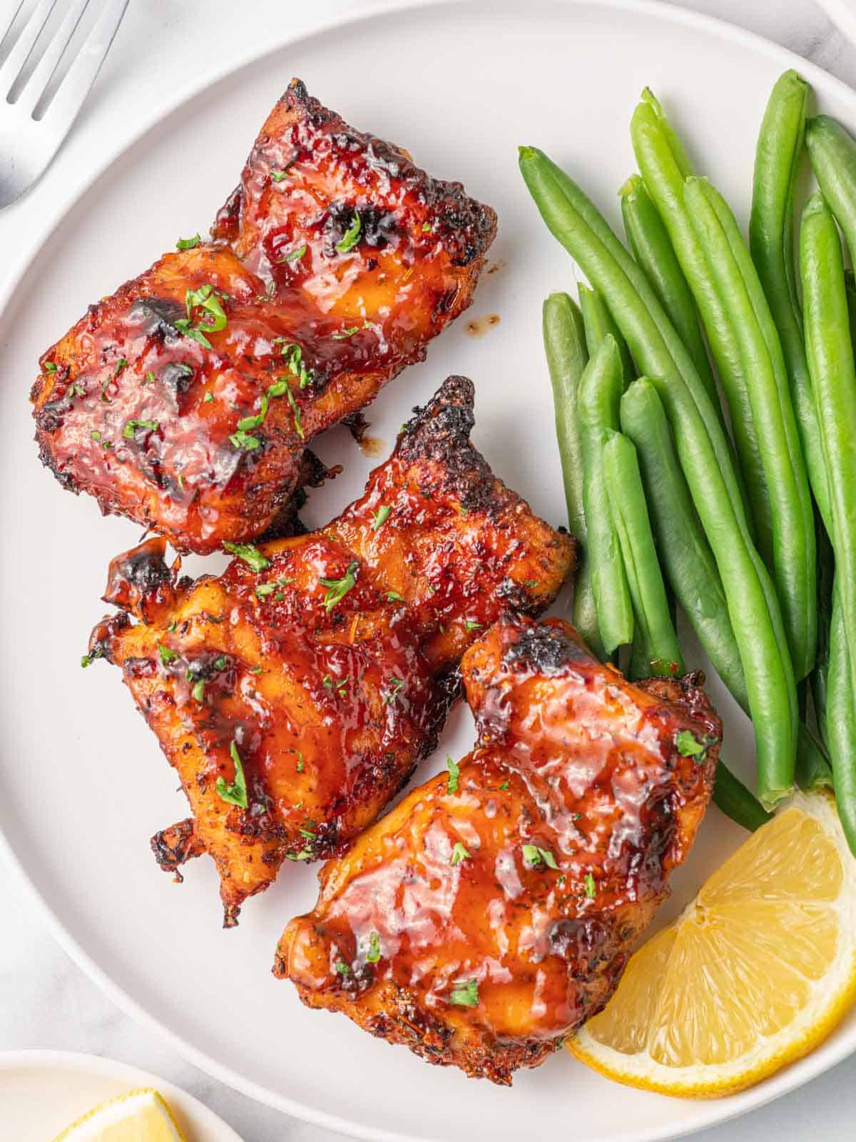Best air fryer chicken thighs on a plate with green beans.