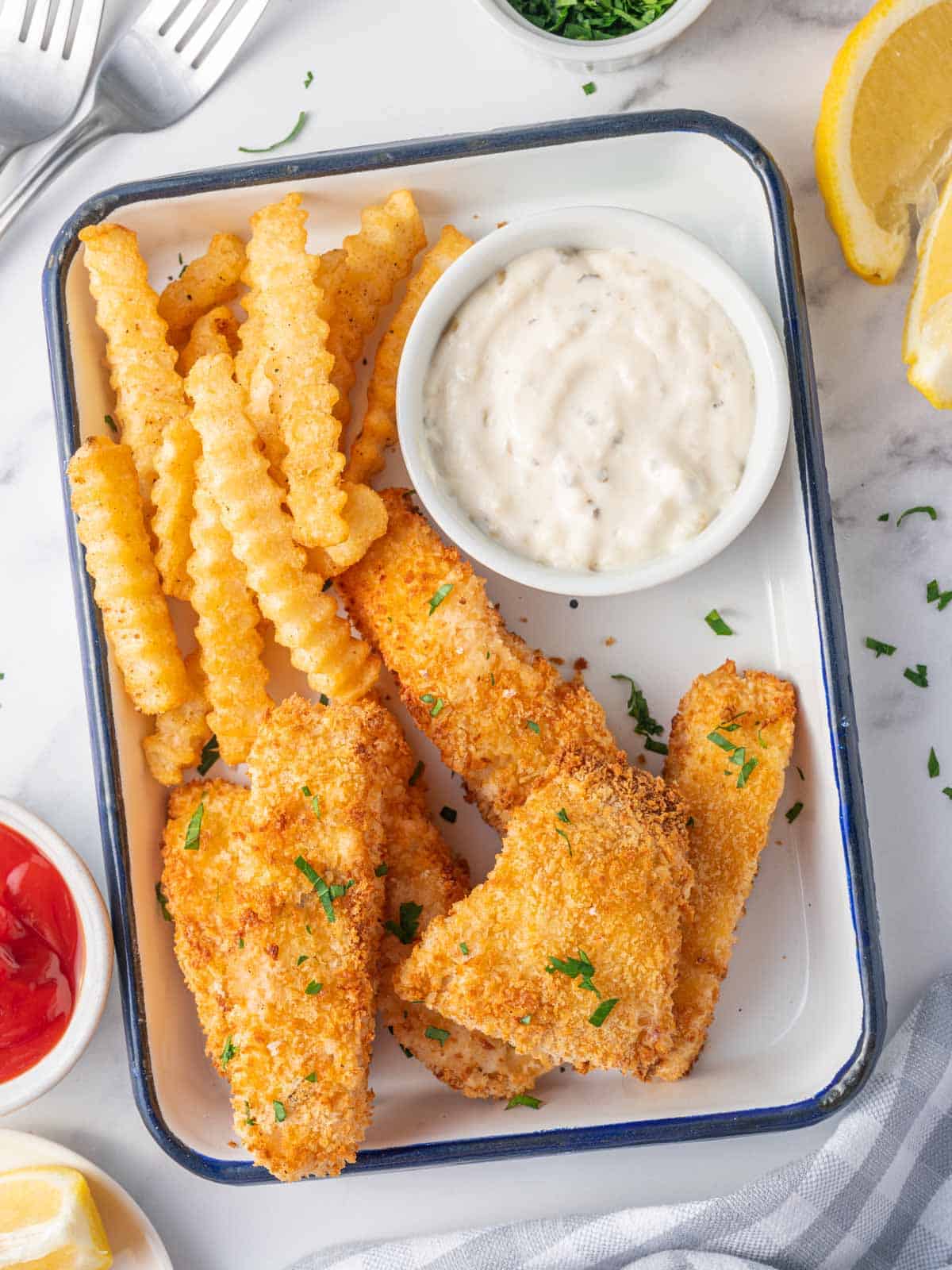 Fish and chips on a plate with tarter sauce.