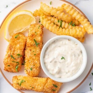 A plate of fish and chips with tarter sauce.