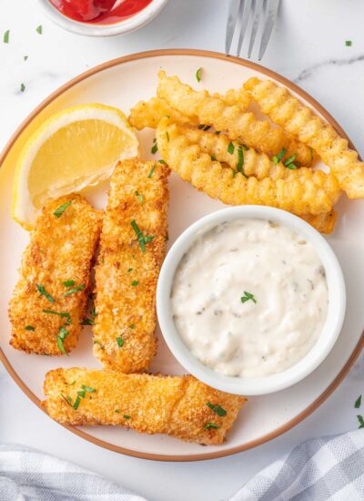 A plate of fish and chips with tarter sauce.