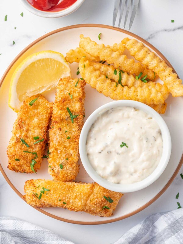 A plate of fish and chips with tarter sauce.