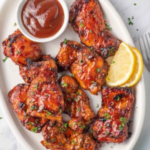 Air fryer bbq chicken on a plate with extra barbecue sauce.