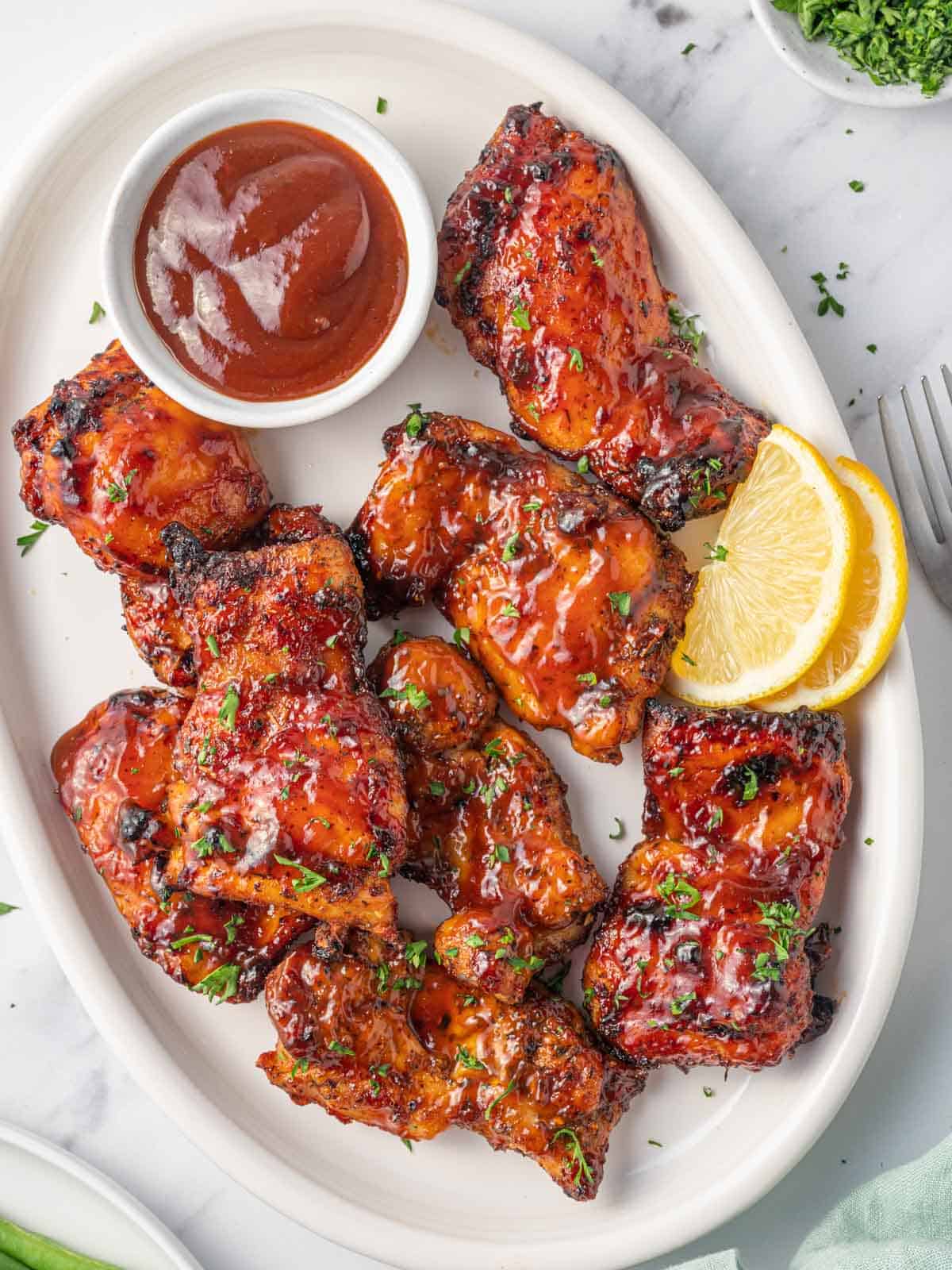 Air fryer bbq chicken on a plate with extra barbecue sauce.