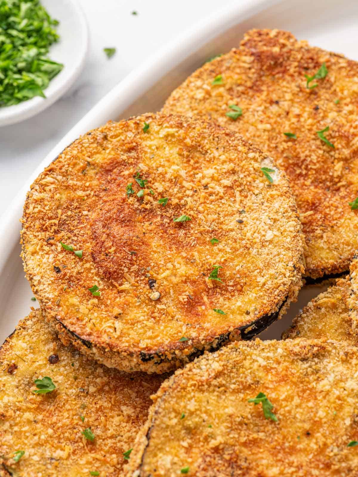 Golden, crispy fried eggplant garnished with parsley.