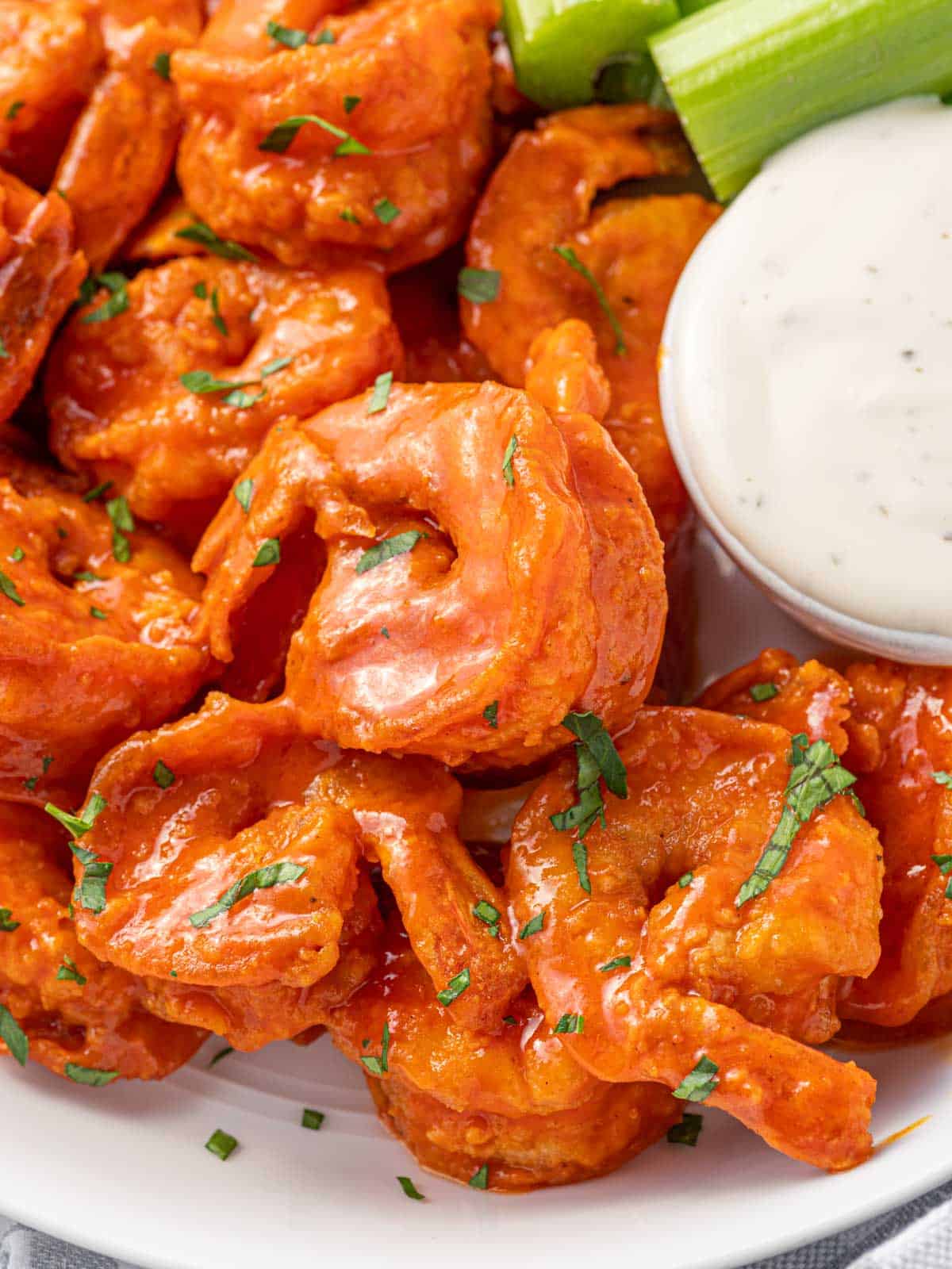 Closeup of spicy fried shrimp with buffalo sauce and dip.