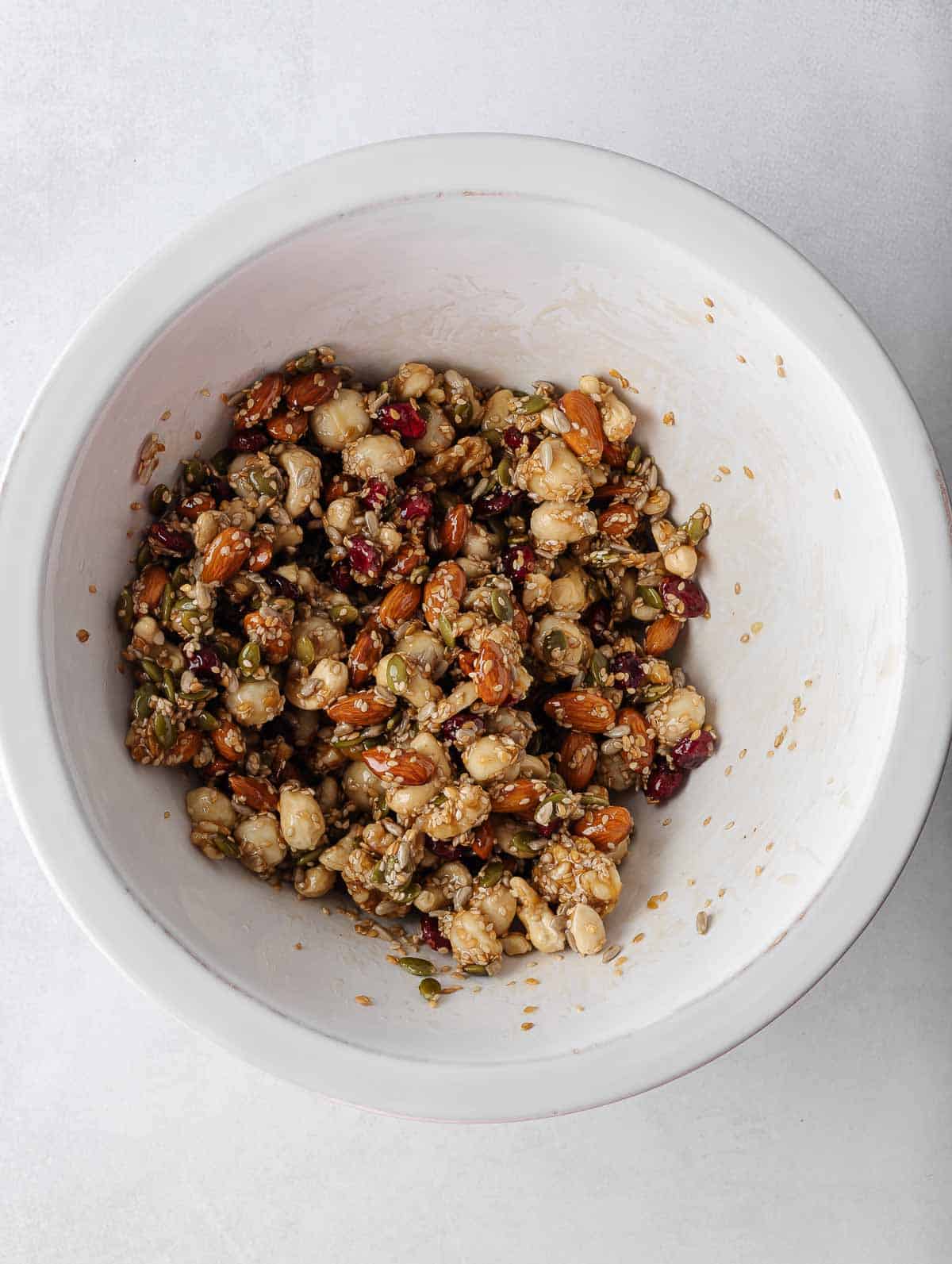 Nuts and seeds combined with honey mixture in a bowl.