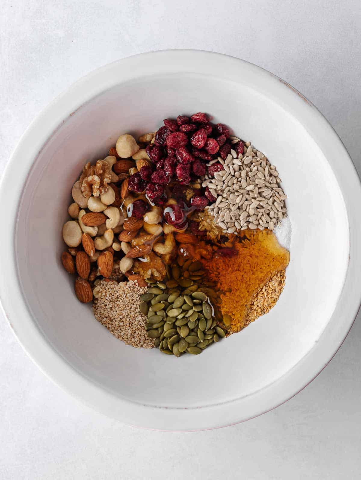 Nuts and seeds combined with honey mixture in a bowl.