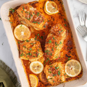 Oven baked Cajun cod fillets with garlic butter sauce, lemon slices, and chopped parsley.