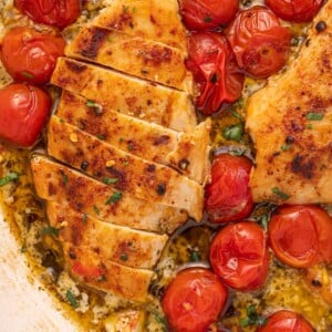 Chicken breast with creamy pesto cut into slices in a skillet.