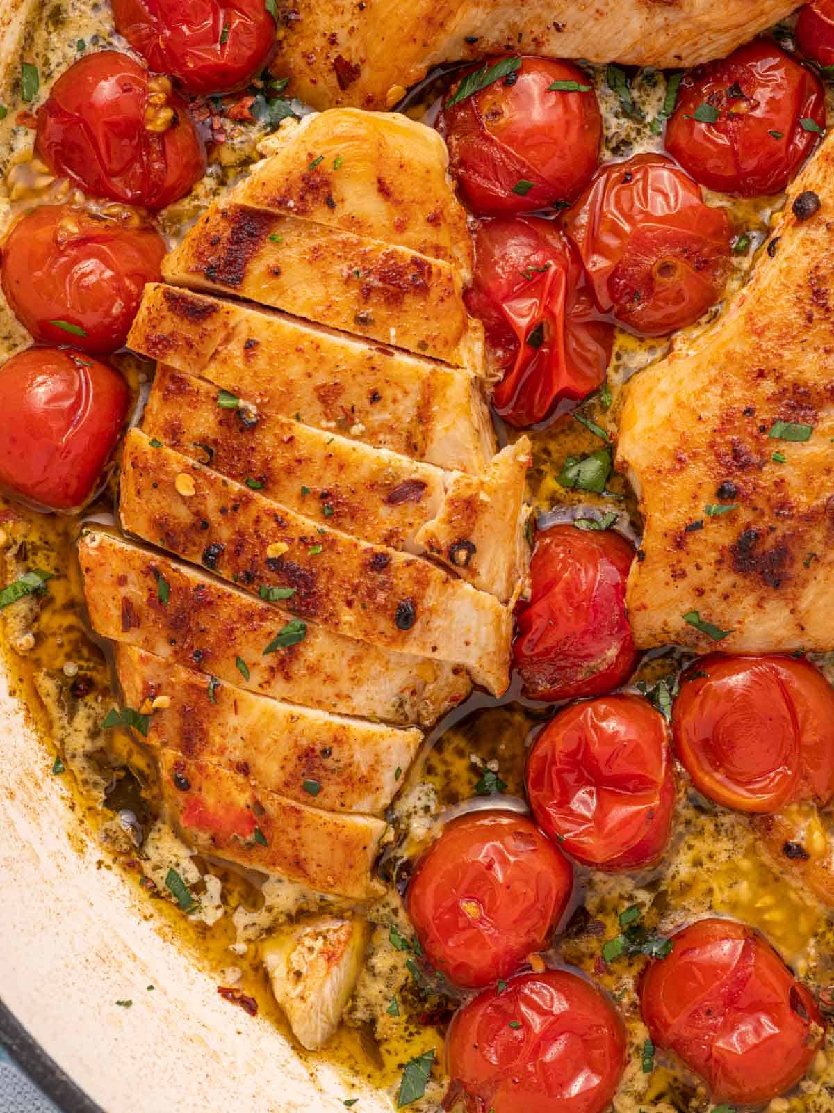 Chicken breast with creamy pesto cut into slices in a skillet.