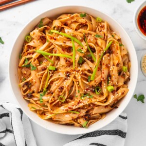 Chopsticks sit beside a bowl of spicy garlic noodles.