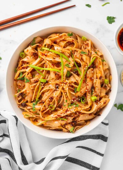 Chopsticks sit beside a bowl of spicy garlic noodles.