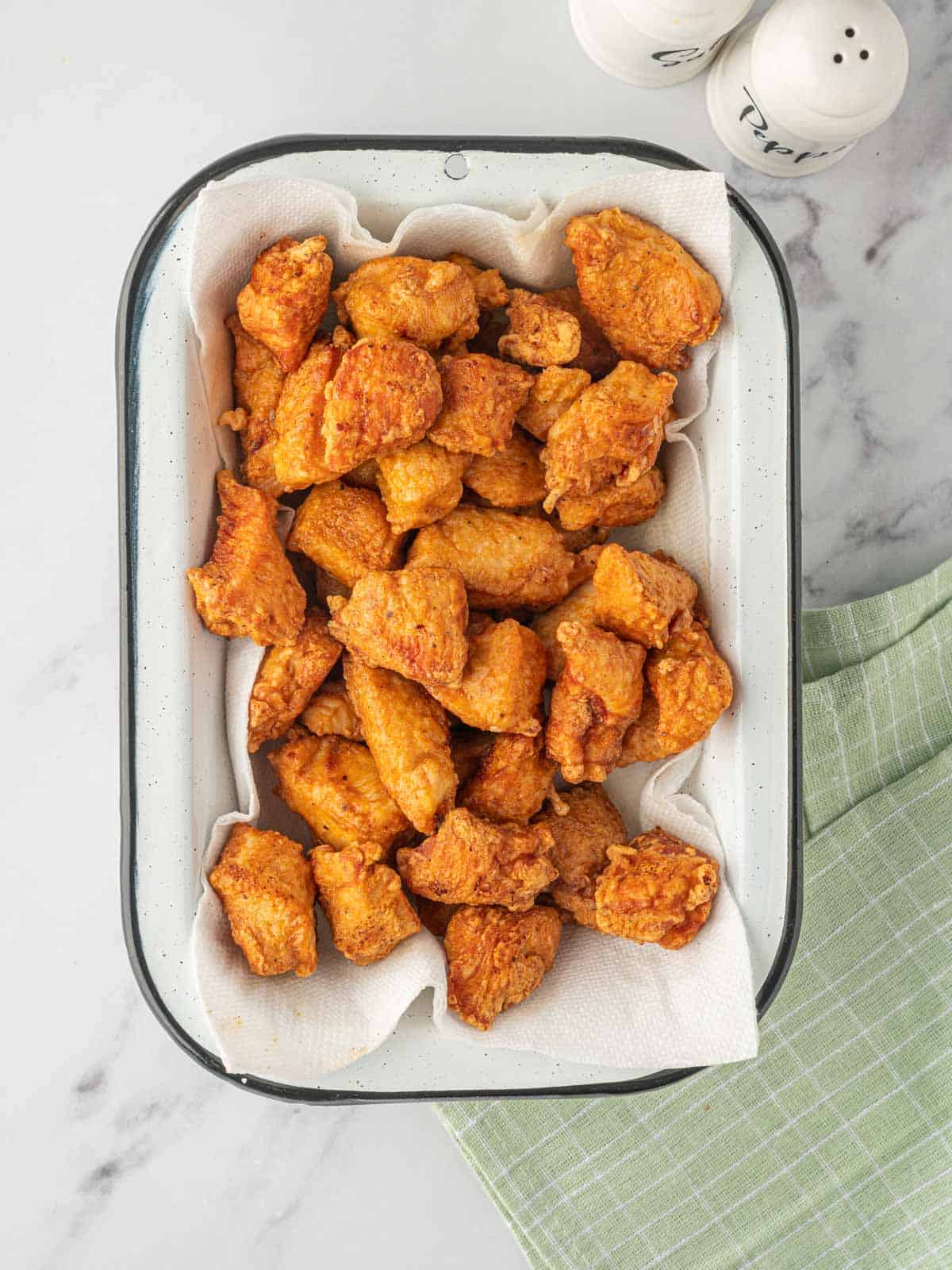 A tray with deep fried chicken on paper towels.