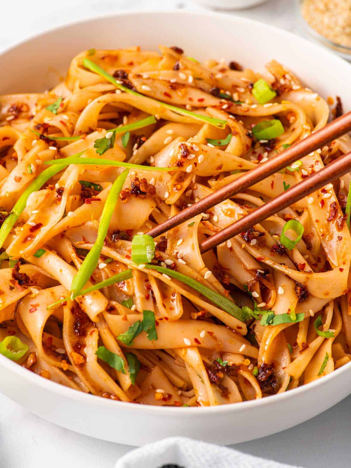 Chopsticks pick up a piece of spicy garlic pasta.