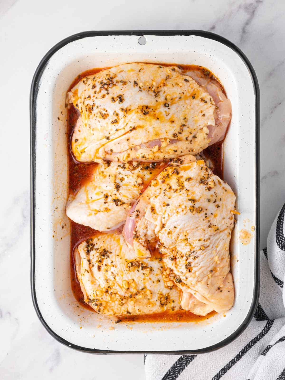 Chicken marinating in a dish.