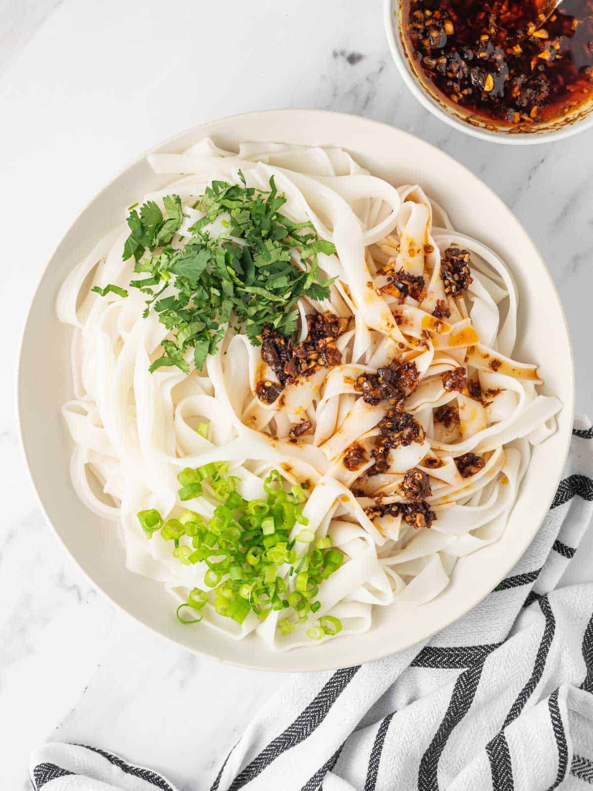 Mixing noodles with chili oil and garnishes.