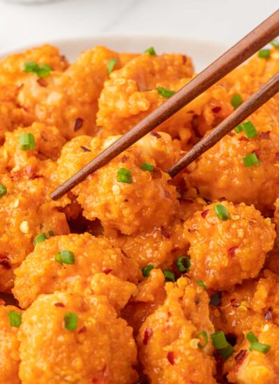 A bowl of baked bang bang cauliflower with chopsticks.