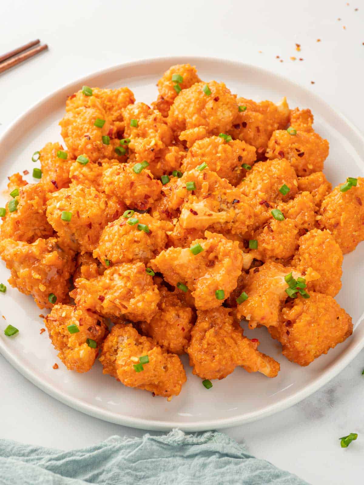 A blate of crispy baked cauliflower tossed with bang bang sauce.