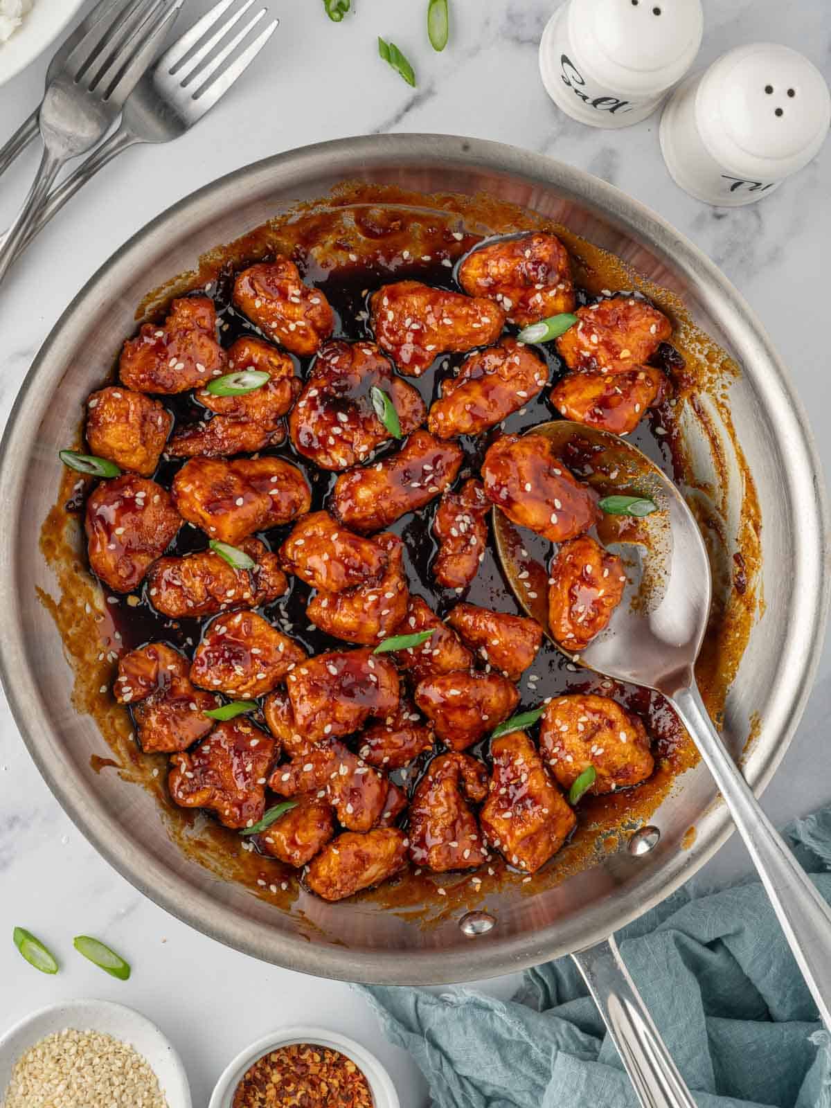 A spoon scoops gochujang sauce of crispy chicken.