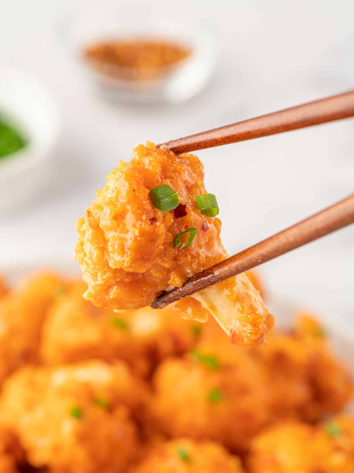 Chopsticks hold a piece of crispy baked cauliflower.