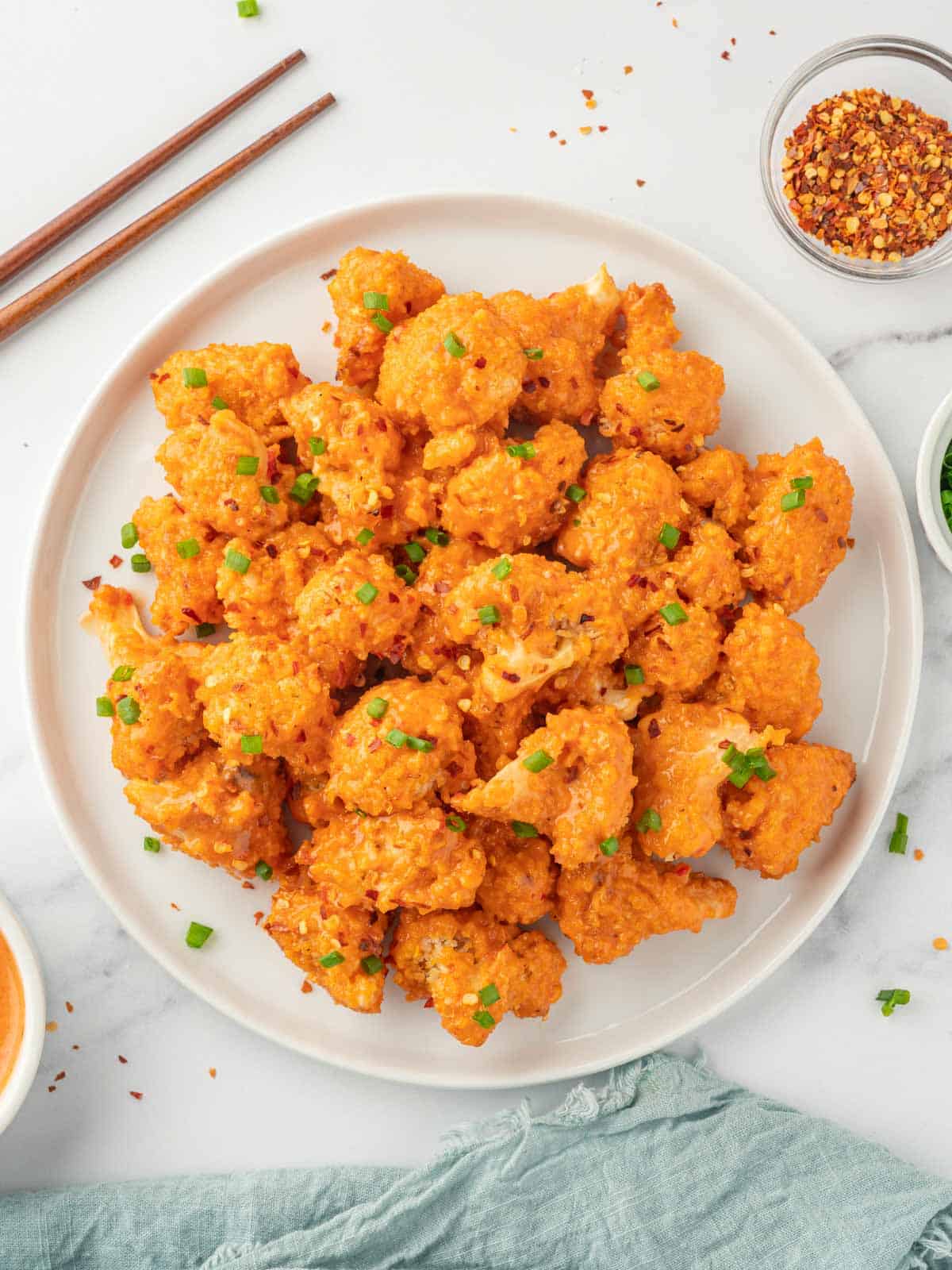 Chopsticks rest beside a plate of baked cauliflower bang bang.