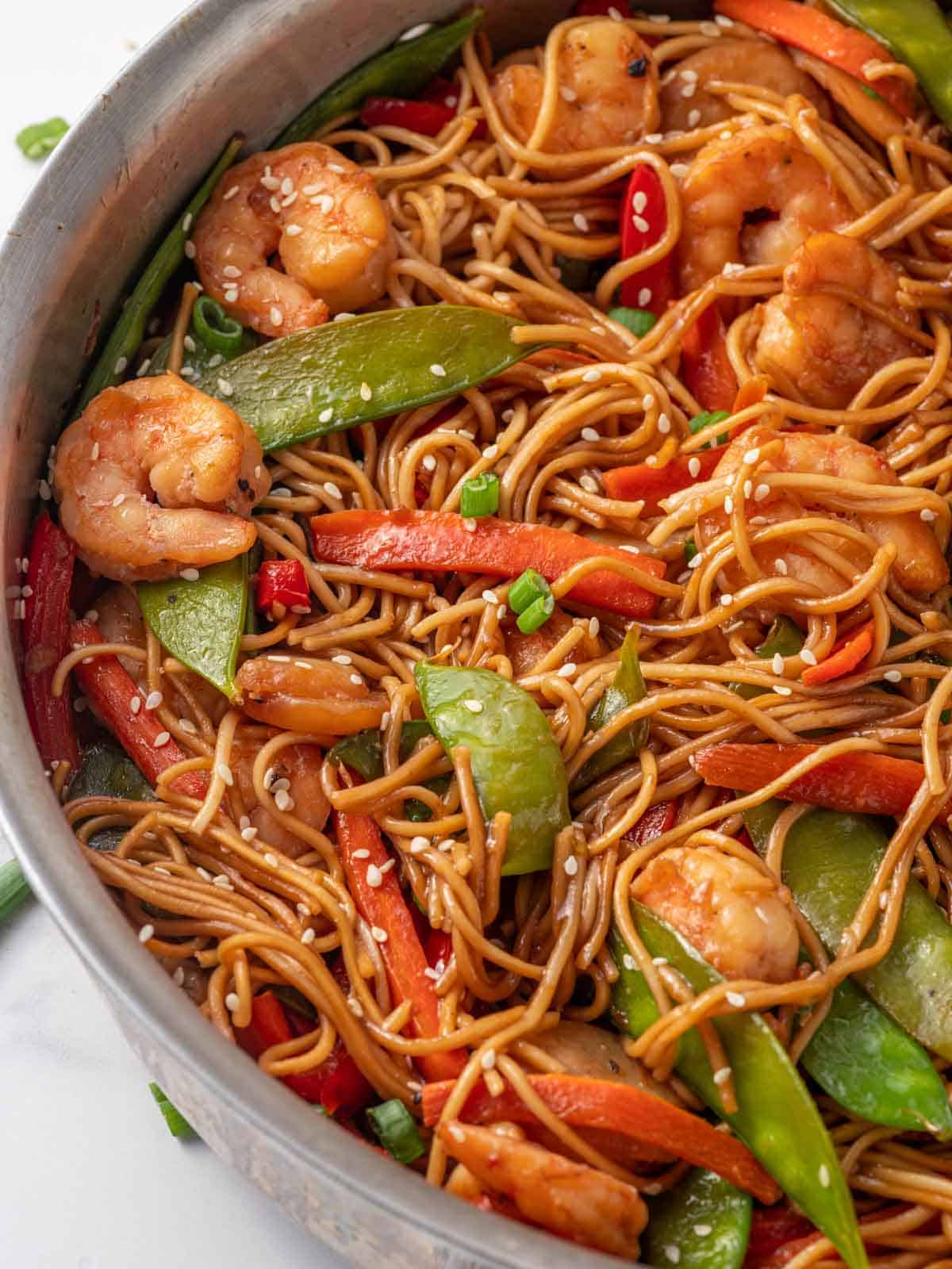A skillet of shrimp noodles with vegetables.