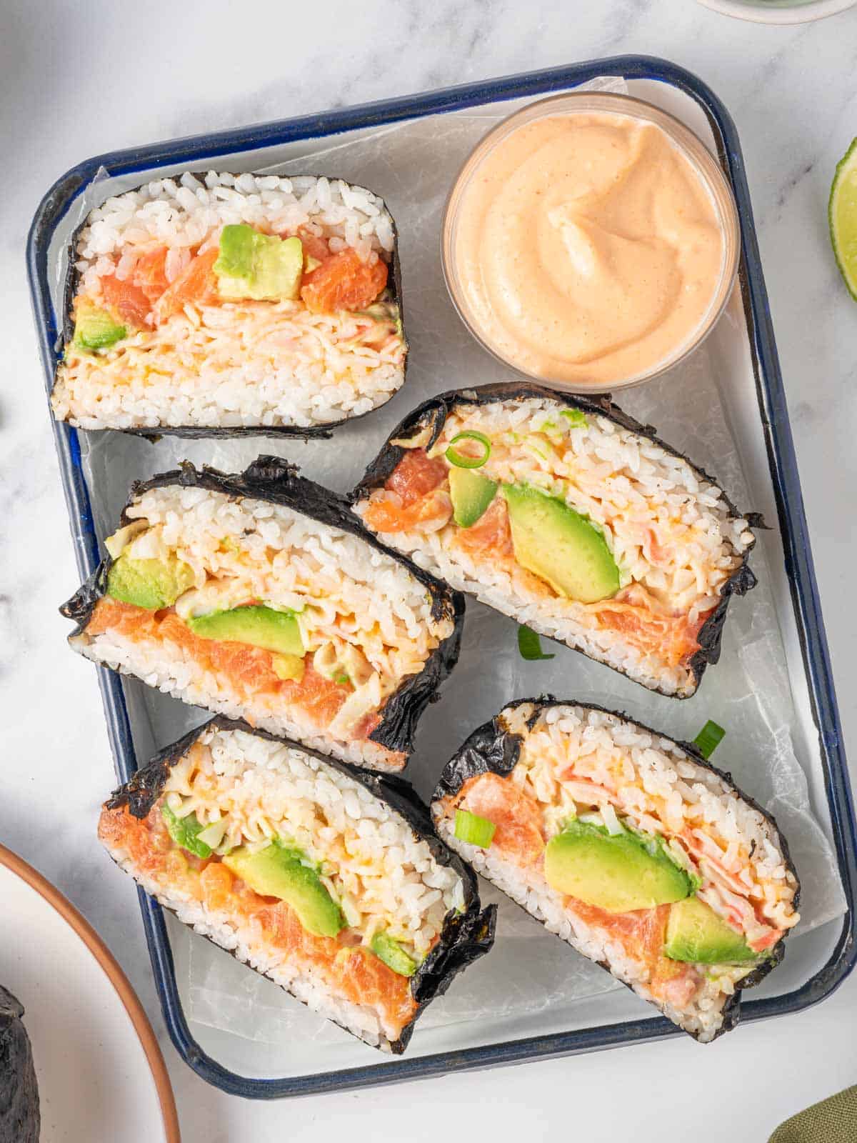 Rice bun sushi burgers sliced in half on a tray.