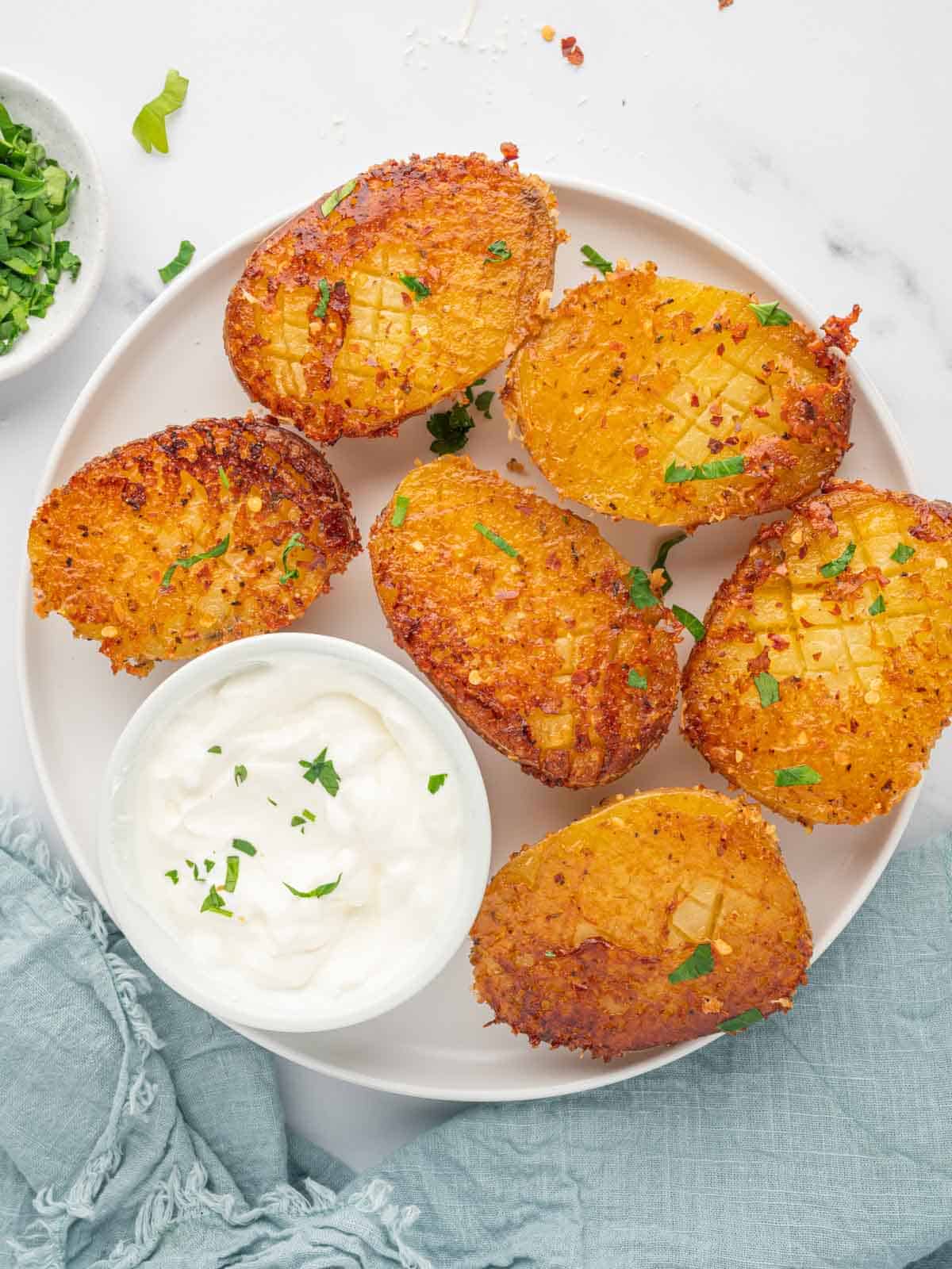 A plate of crispy potatoes with sour cream.