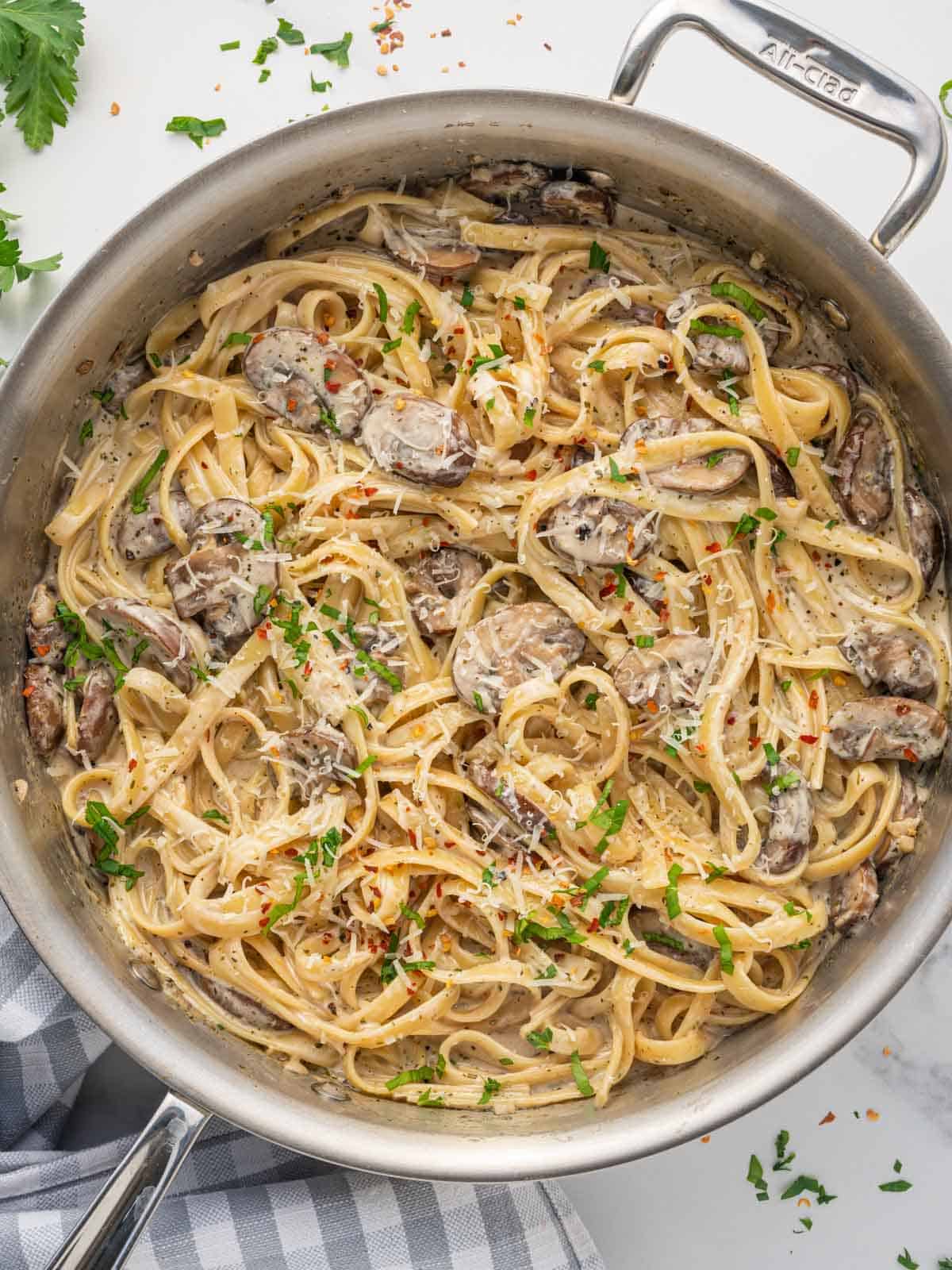 A skillet loaded with fettuccine with mushroom sauce.