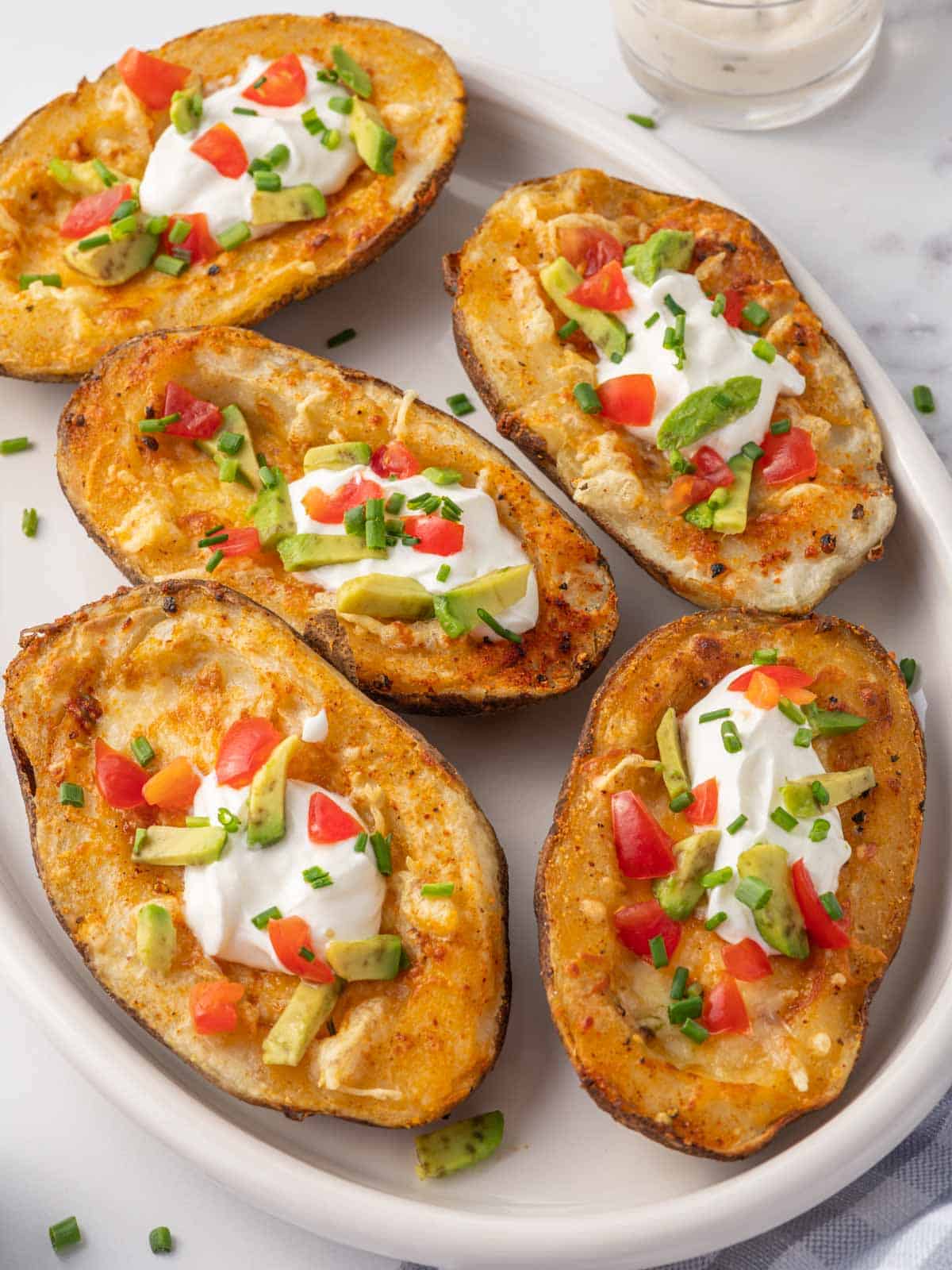 Crispy potato skins topped with cheese, sour cream, avocado and tomato.