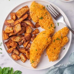 Chicken tenders and potatoes on a plate with a fork.