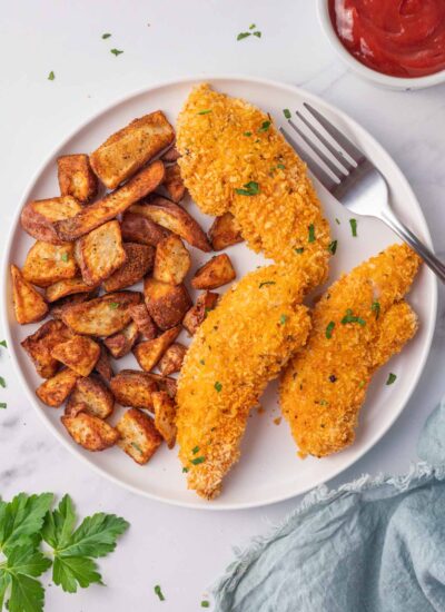 Chicken tenders and potatoes on a plate with a fork.