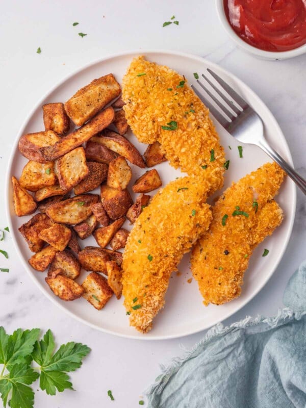 Chicken tenders and potatoes on a plate with a fork.