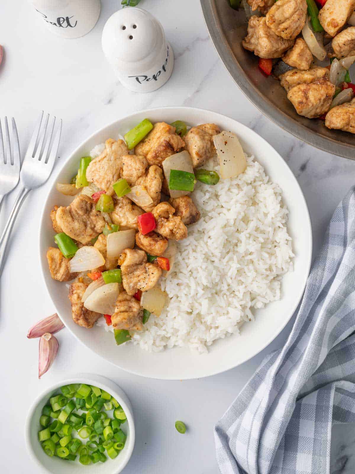 Crispy salt and pepper chicken with rice on a plate.