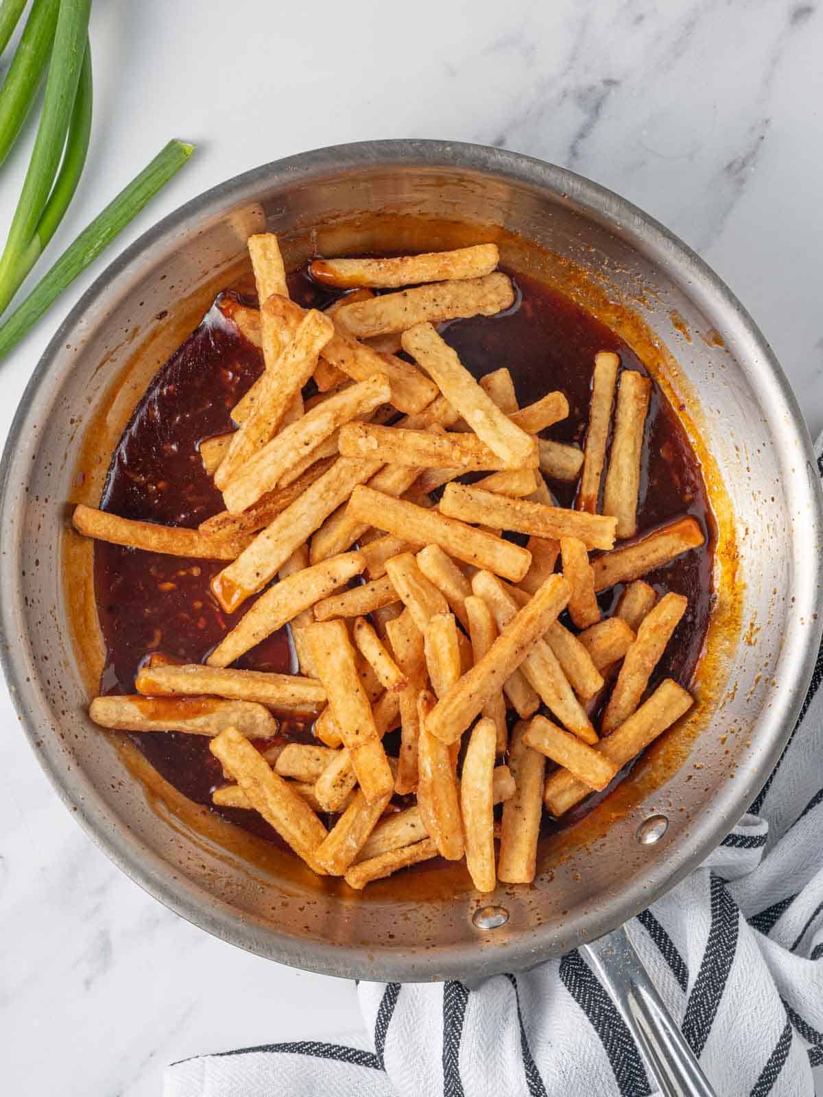 Tossing fries in spicy sauce.