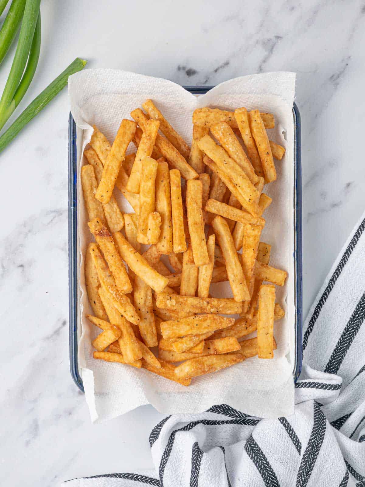 Cooked fries drain on a paper towel.