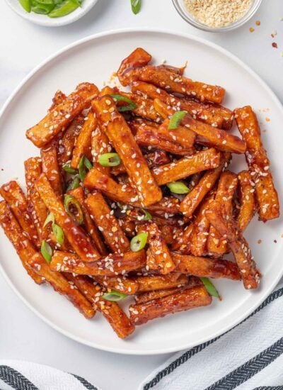 A plate of chilli fries topped with sesame seeds and green onions.
