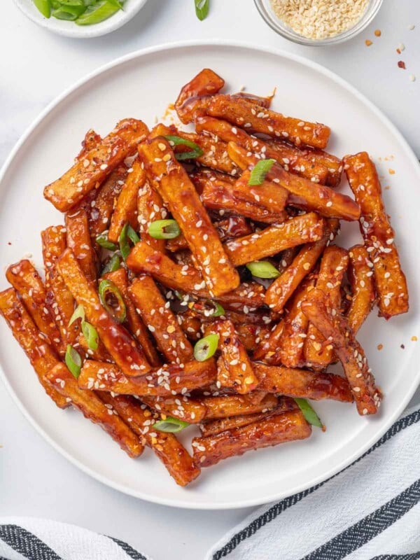 A plate of chilli fries topped with sesame seeds and green onions.