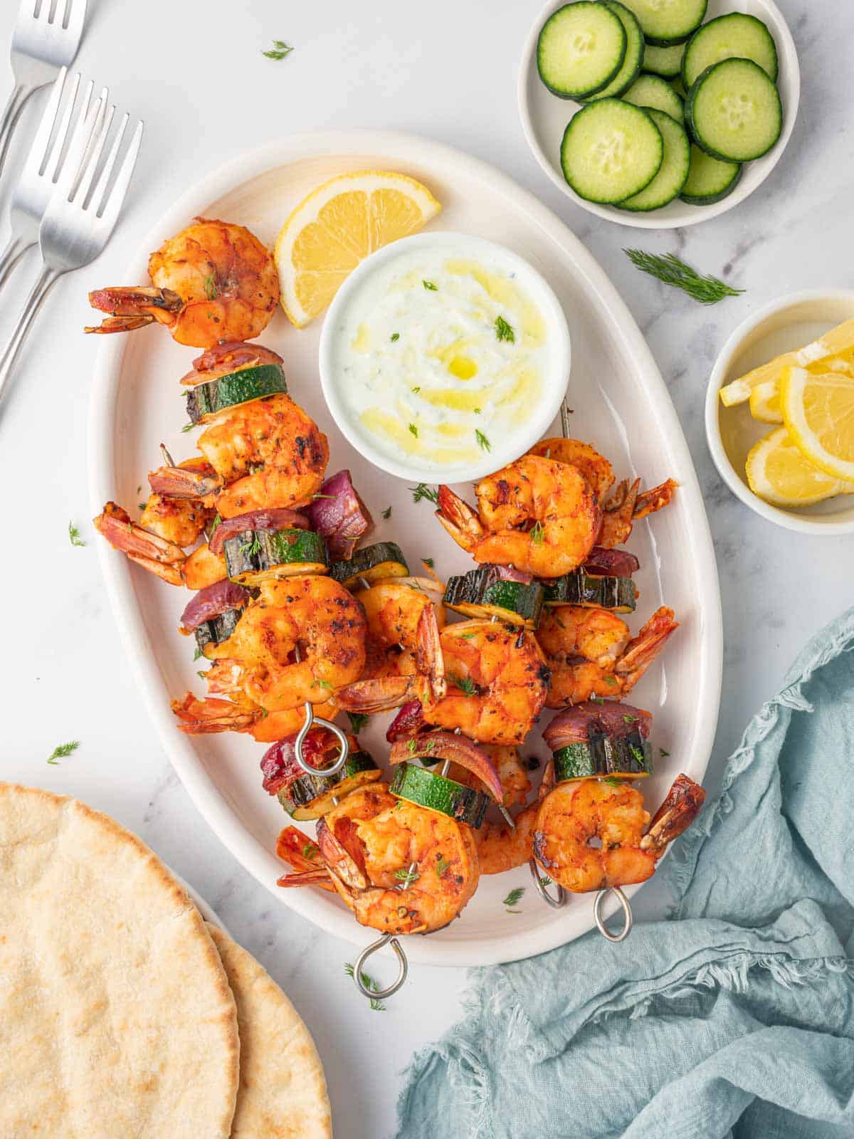 A platter of grilled shrimp with zucchini and onions.