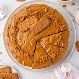 A whole biscoff cheese cake is cut into slices.