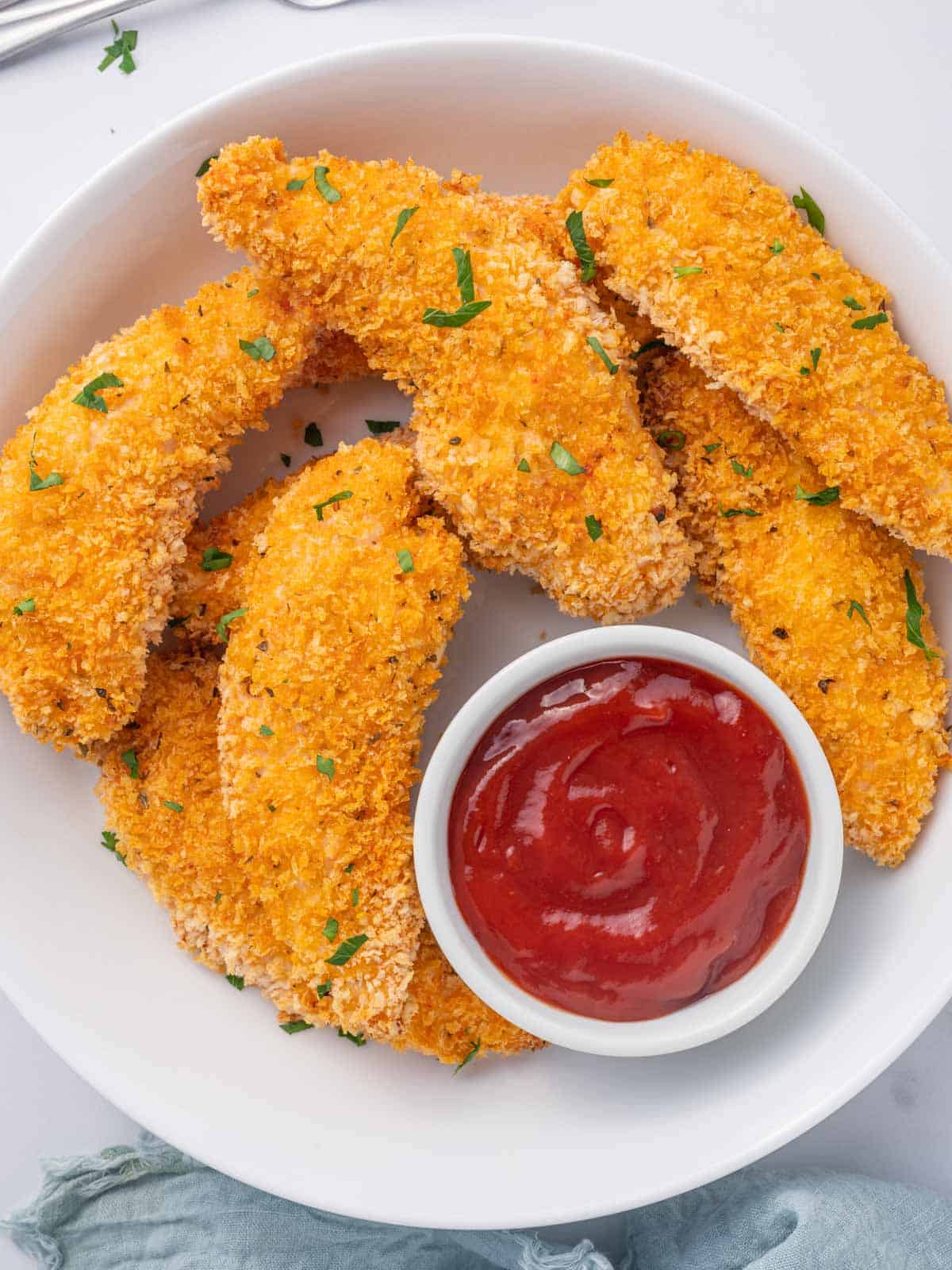 Panko crusted chicken on a plate with ketchup.