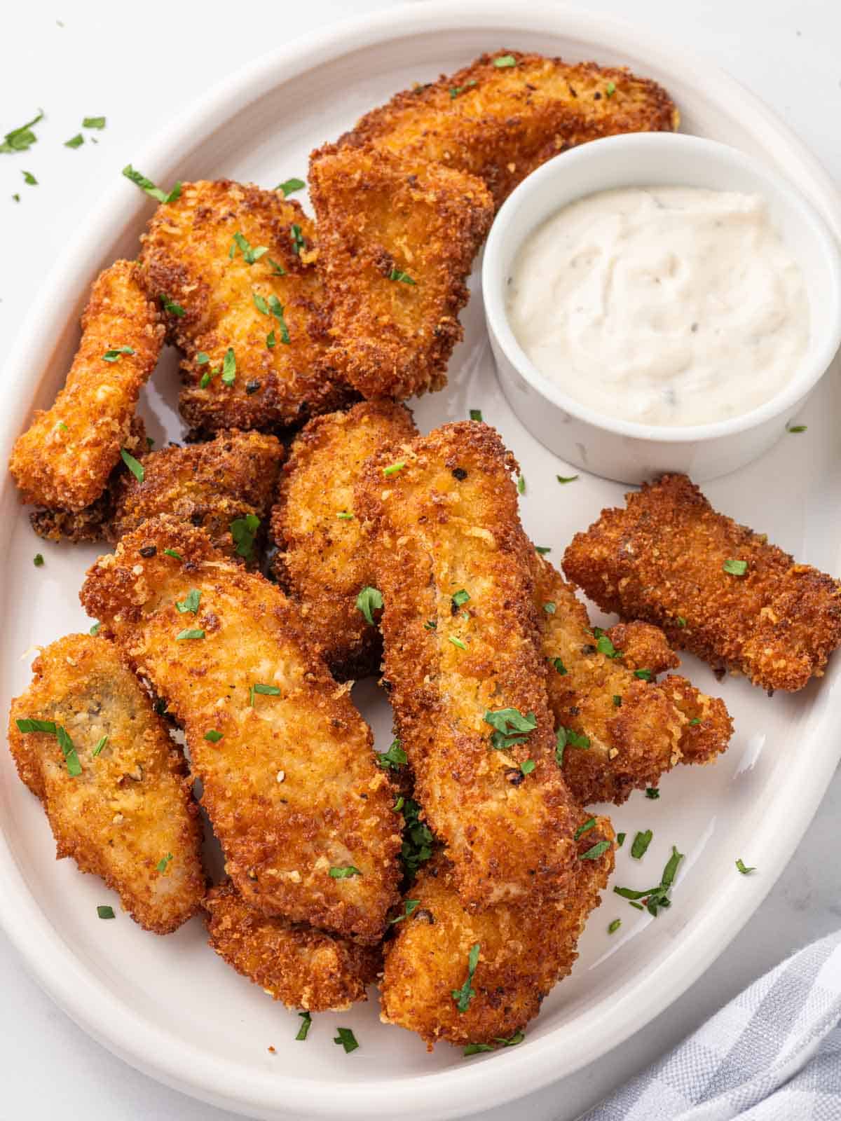 A plate of crispy fried fish with dip.