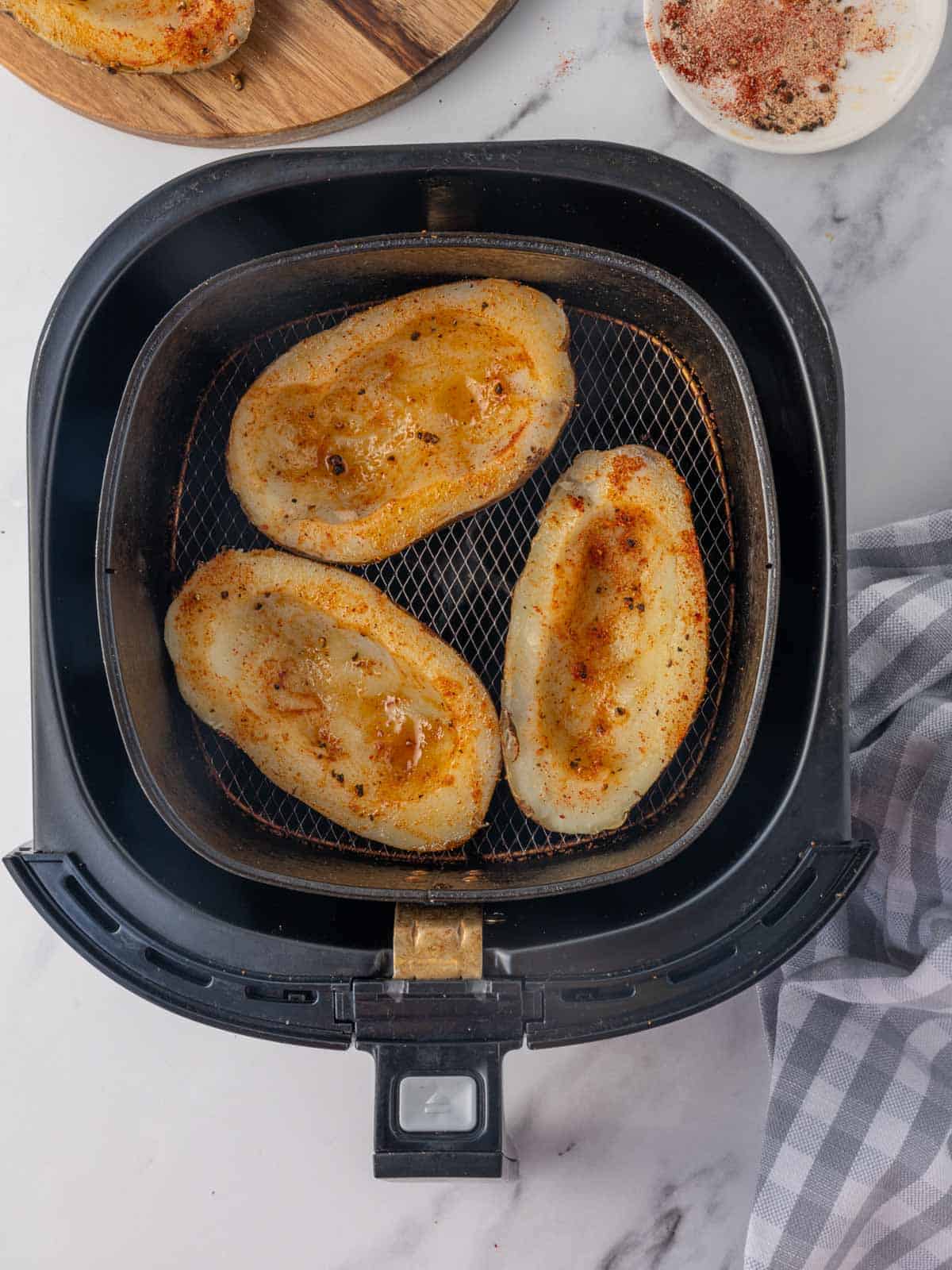 Seasoned potato skins in an air fryer basket.