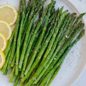 A plate of asparagus with lemon slices.