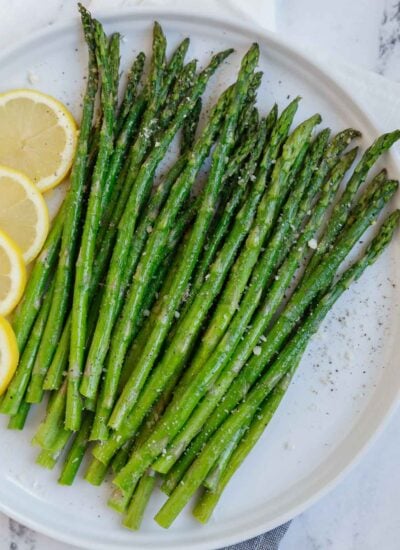 A plate of asparagus with lemon slices.