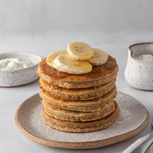 A stack of protein pancakes topped with banana slices.