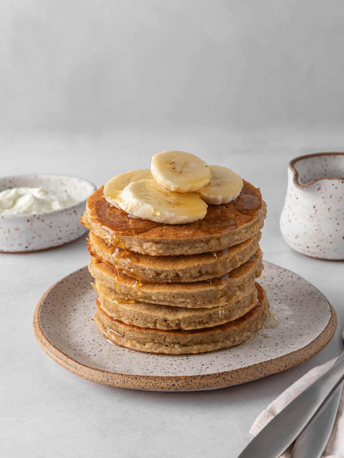 A stack of protein pancakes topped with banana slices.