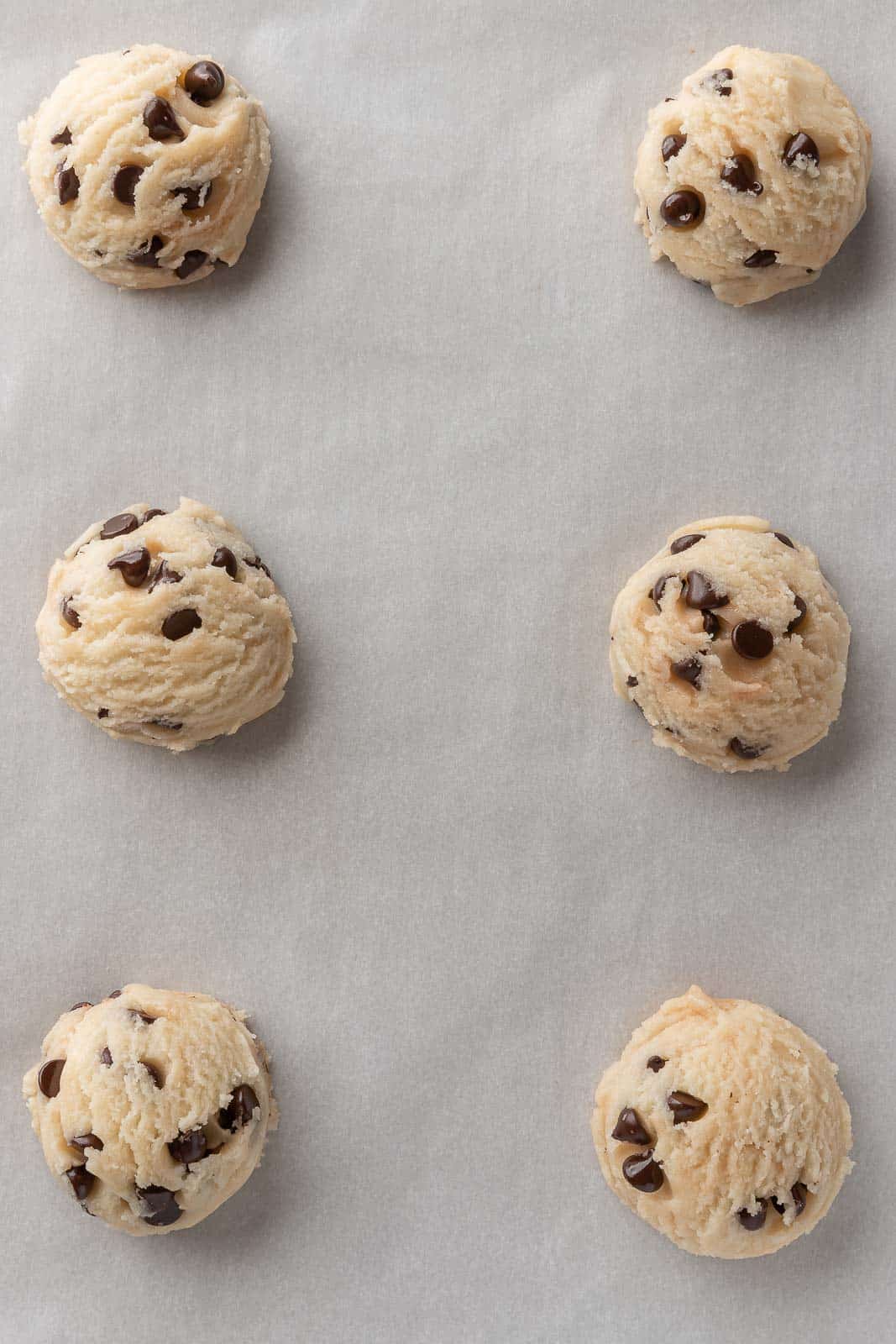Scoops of egg free cookie dough on parchment paper.