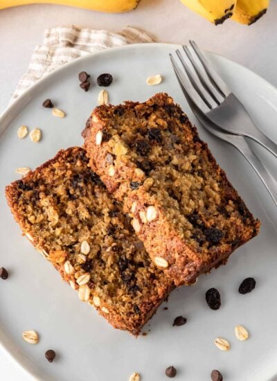 Two slices of banana bread with oats on a plate with two forks.