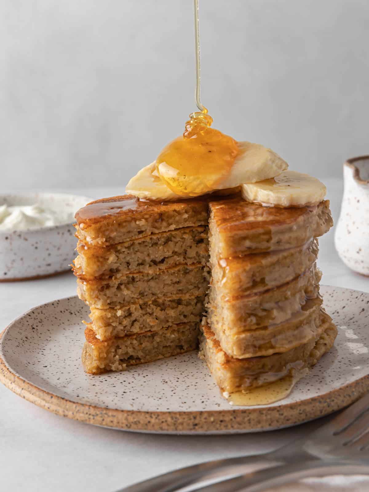 Syrup drizzles onto a stack of protein pancakes.
